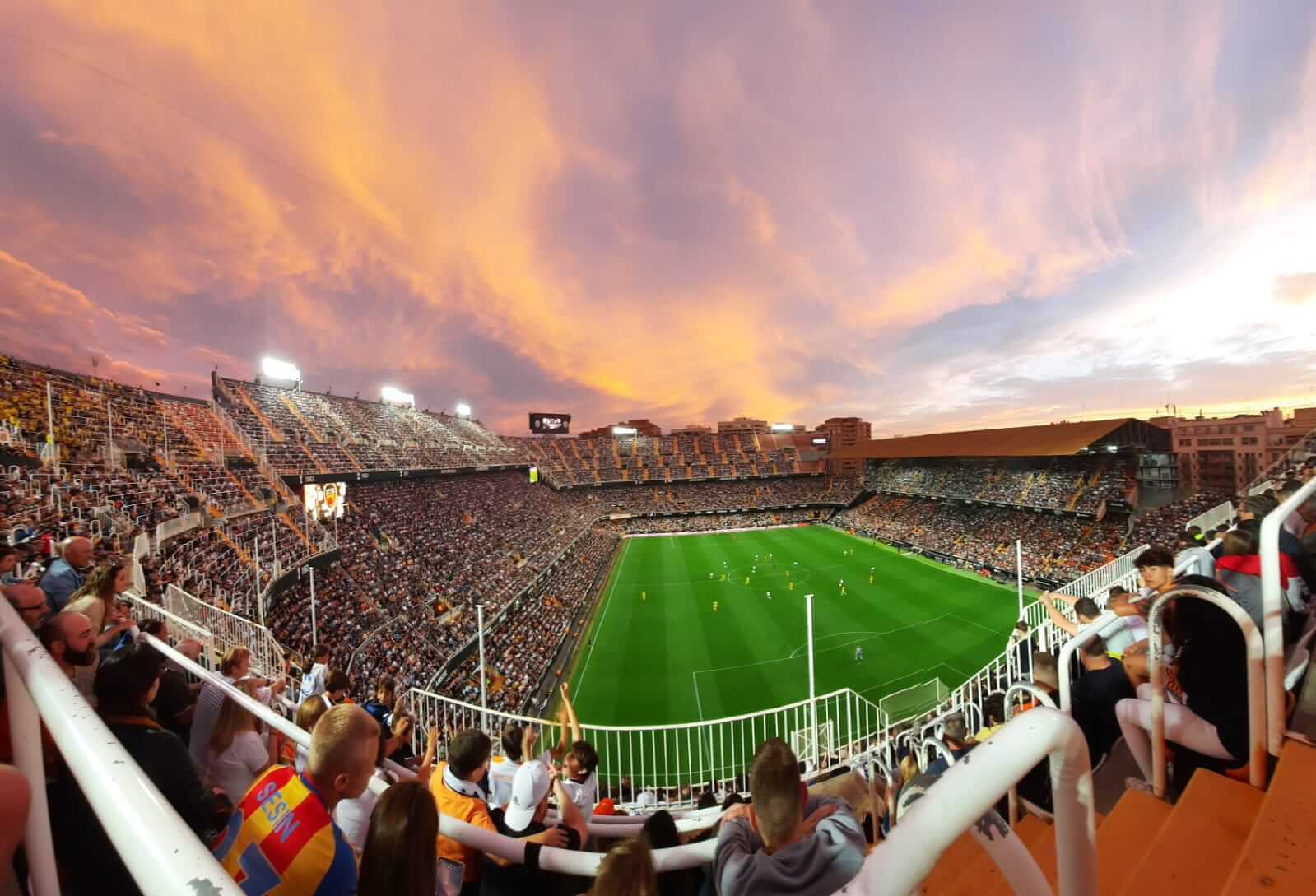 Panorama van Mestalla bij zonsondergang met oranje-roze lucht boven de tribunes