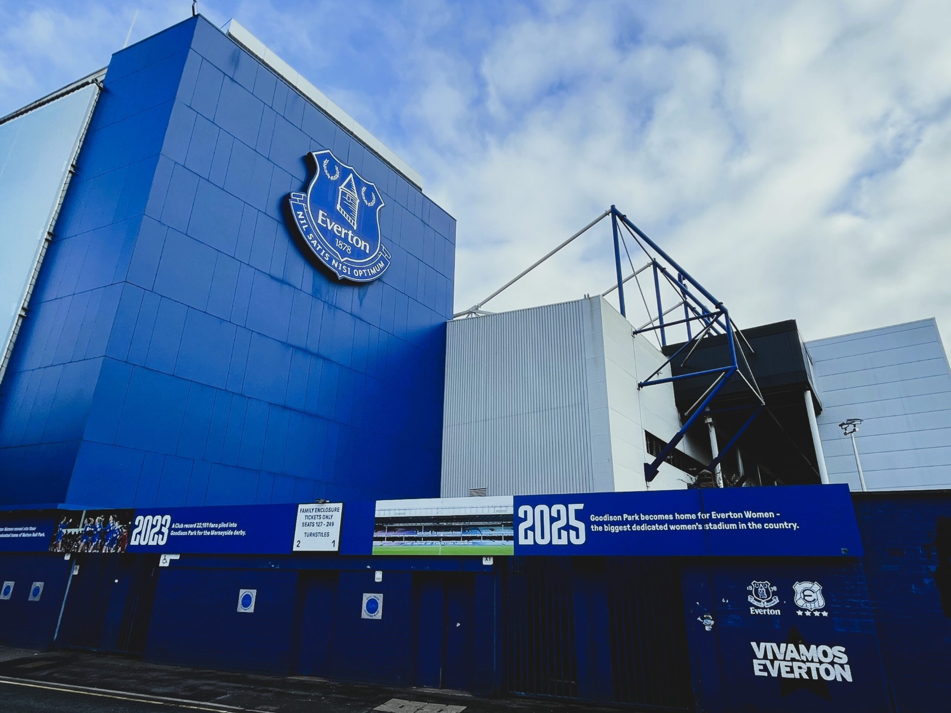 Goodison Park met het Everton clublogo op de blauwe gevel en de Vivamos Everton banier