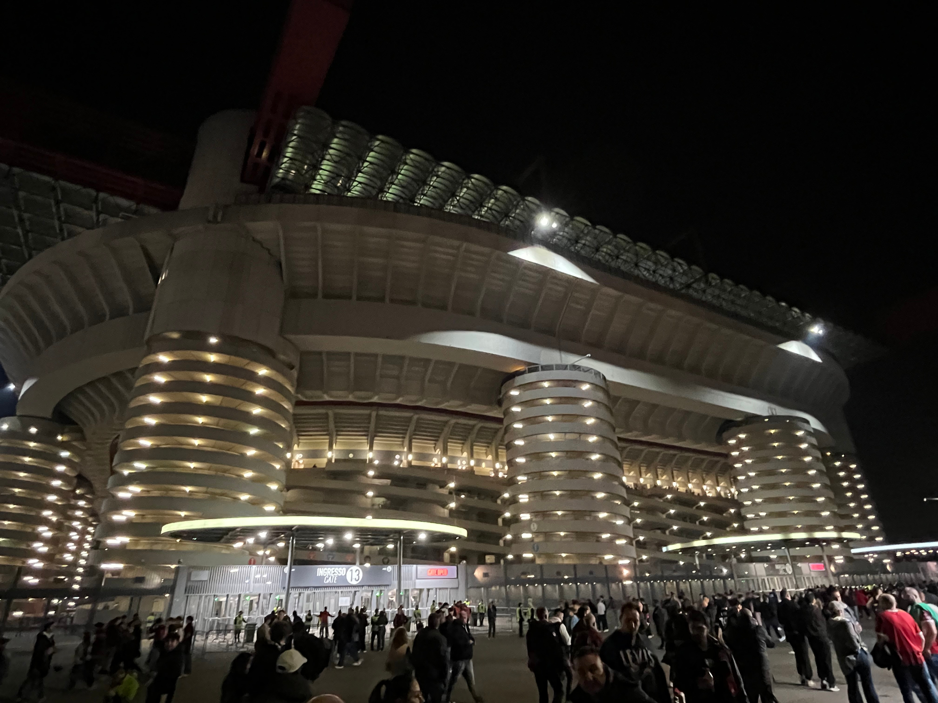 Het verlichte San Siro stadion bij avond met fans bij Ingresso 13 voor een wedstrijd van AC Milan
