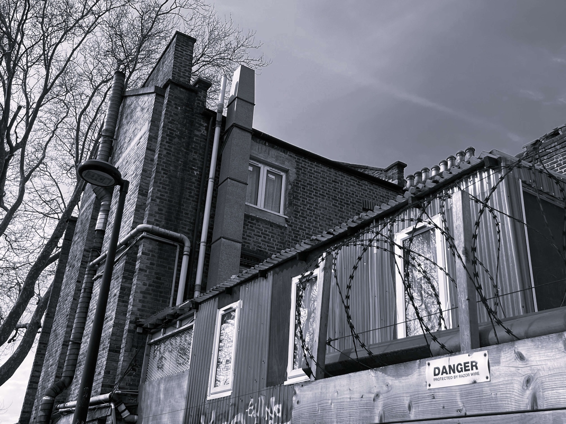 Sfeerbeeld in zwart-wit van de typische Londense bakstenen huizen rond The Den met razor wire